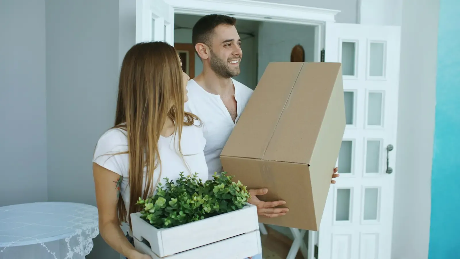 A couple carrying boxes into their home