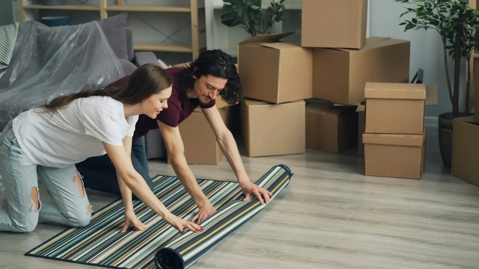 A couple unrolling a rug in their new home among boxes