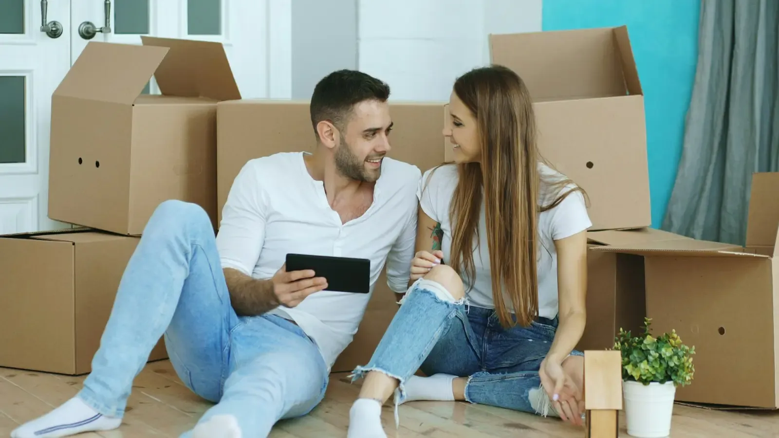 A couple looking at a tablet among boxes