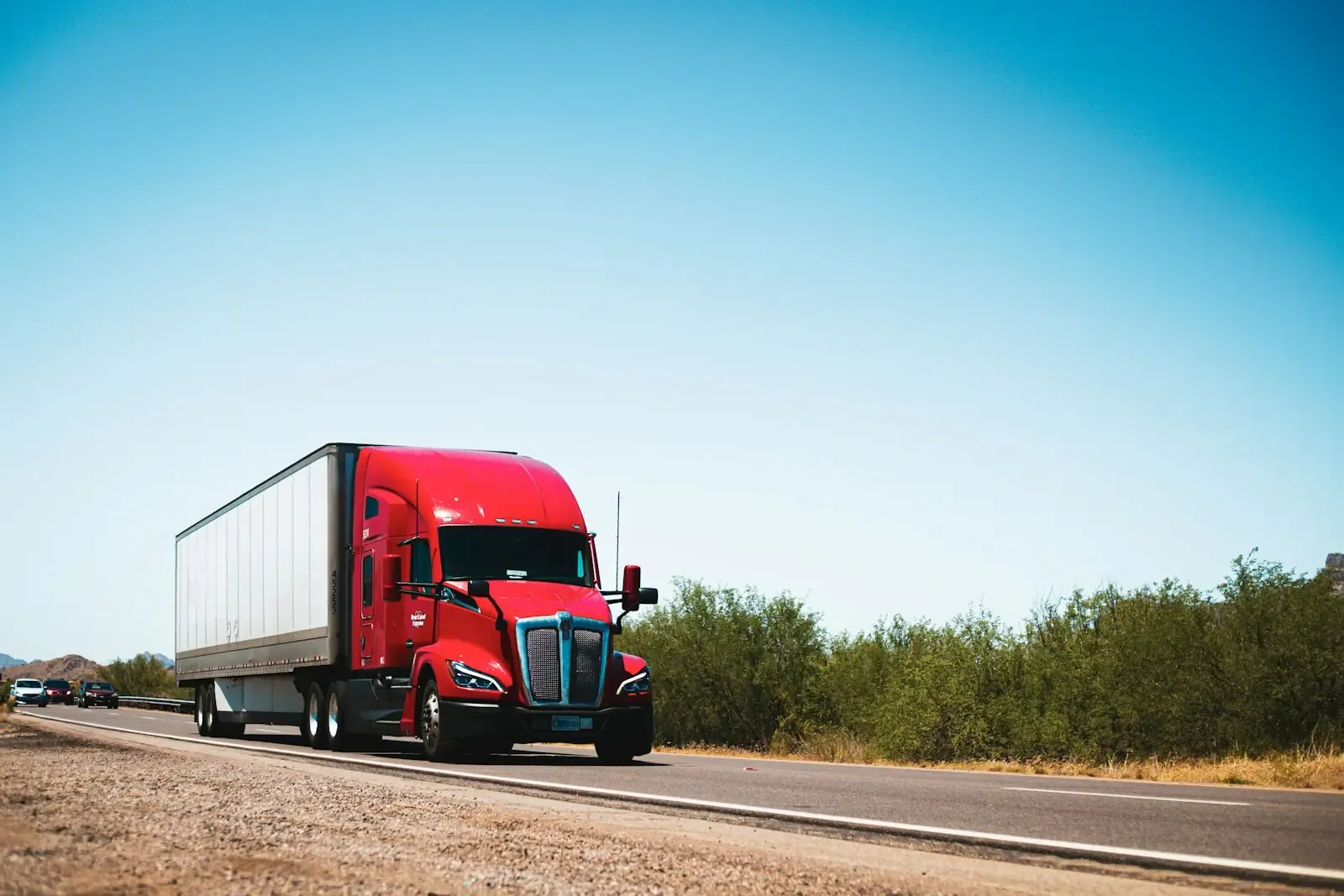 A red semi truck on a country road